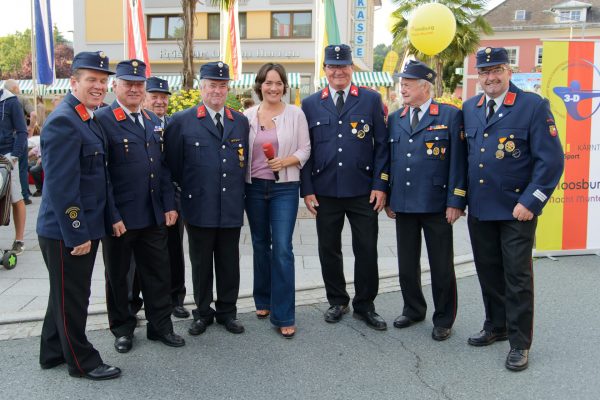 Moderatorin Eva Pölzl mit einer Abordnung der Feuerwehr